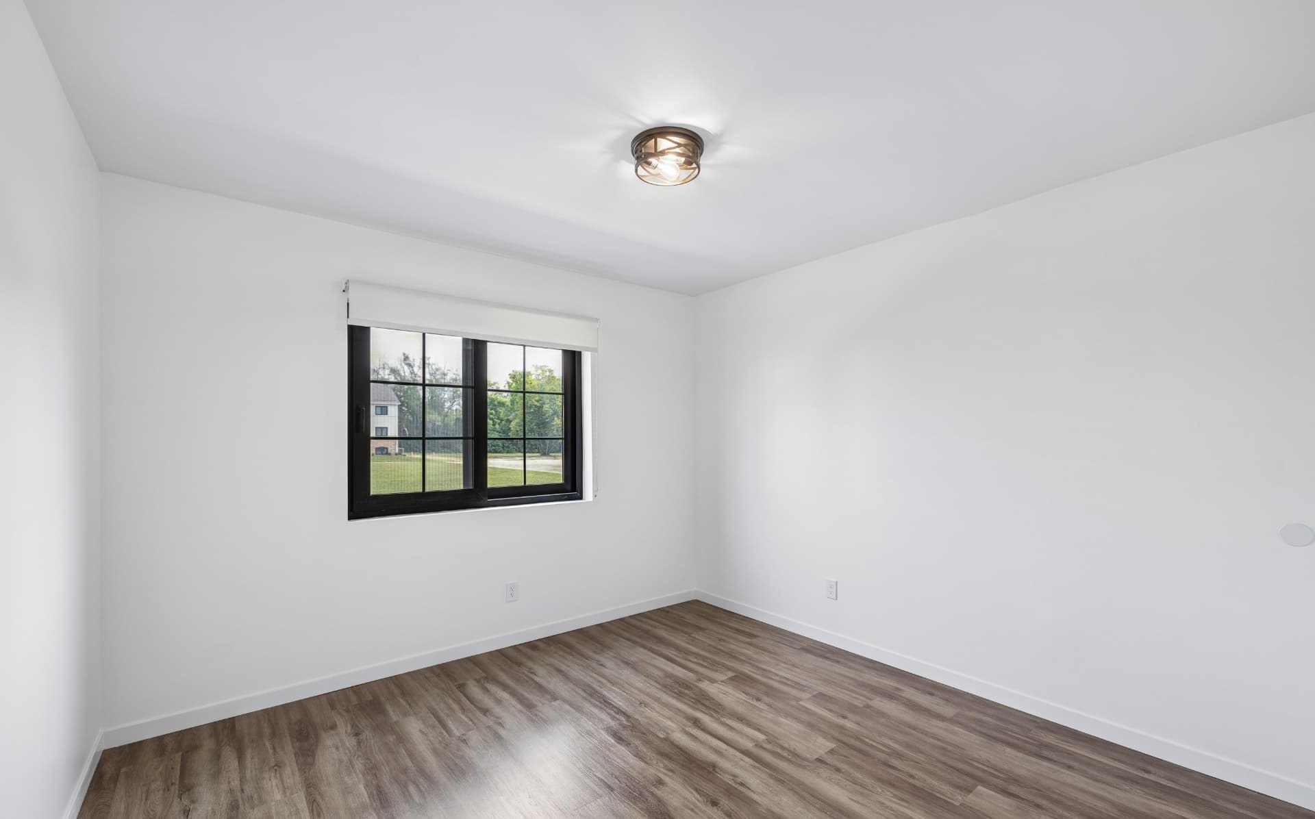 Sunlit bedroom with large window and wood-style flooring