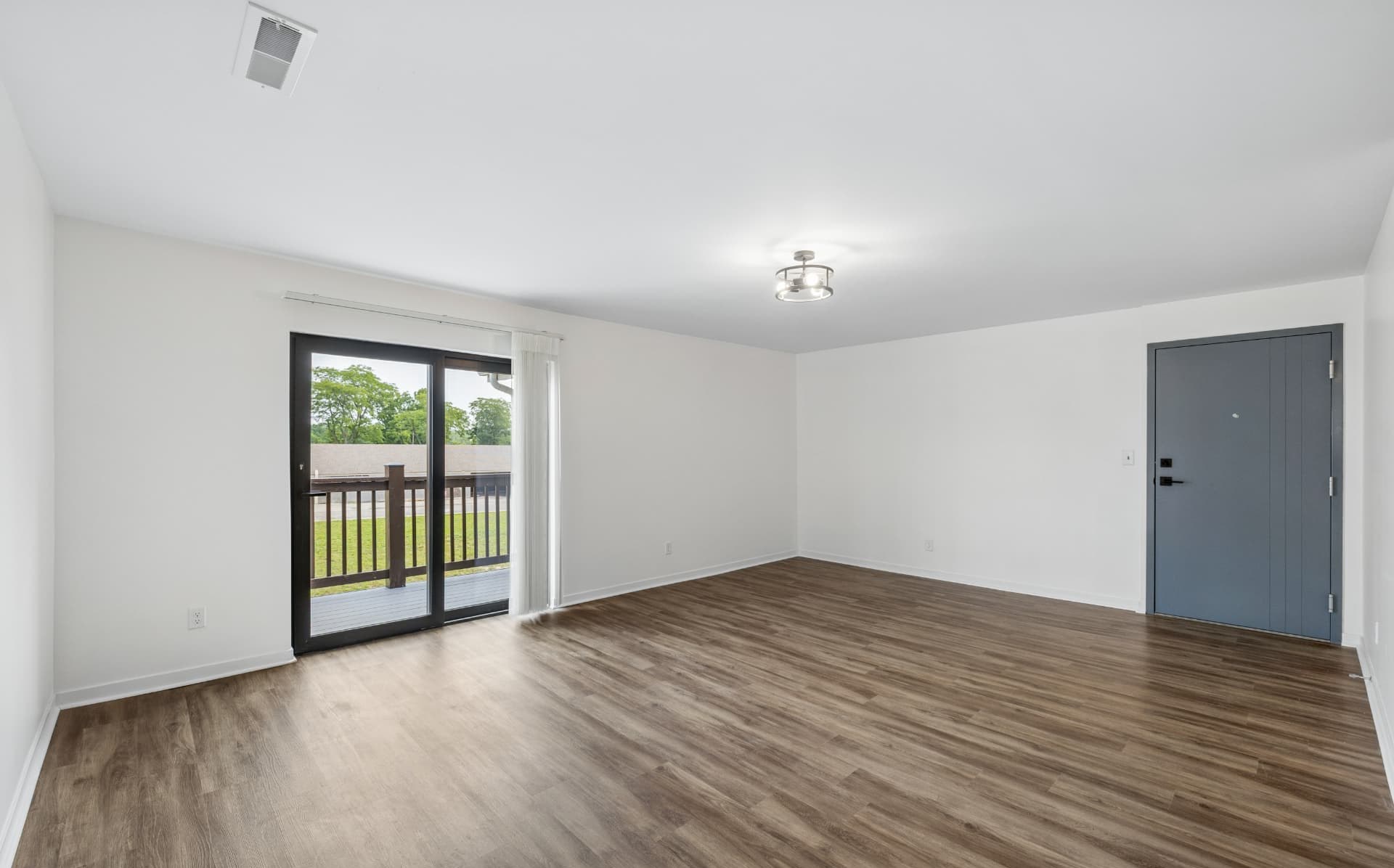Bright living room with luxury vinyl plank flooring and balcony access